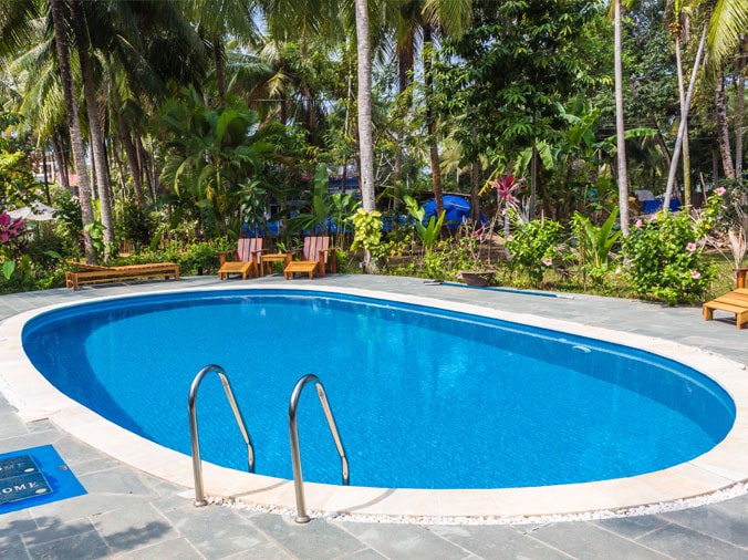 Oval back yard pool with lounge chairs