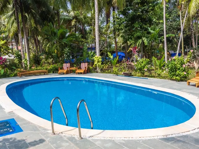 Oval back yard pool with lounge chairs